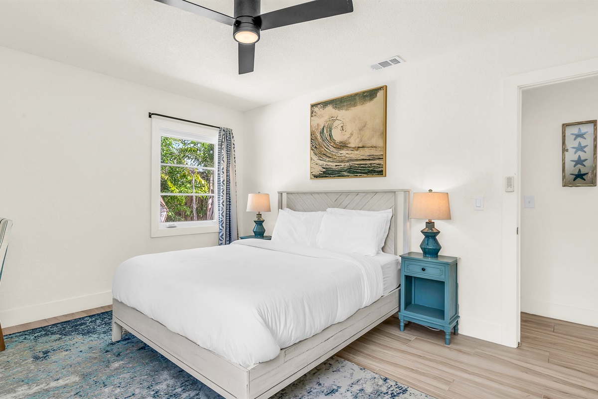 Bedroom 3 features bright coastal decor, crisp white linens, and pops of ocean blue- creating a serene and cheerful retreat for guests to relax and unwind in comfort.