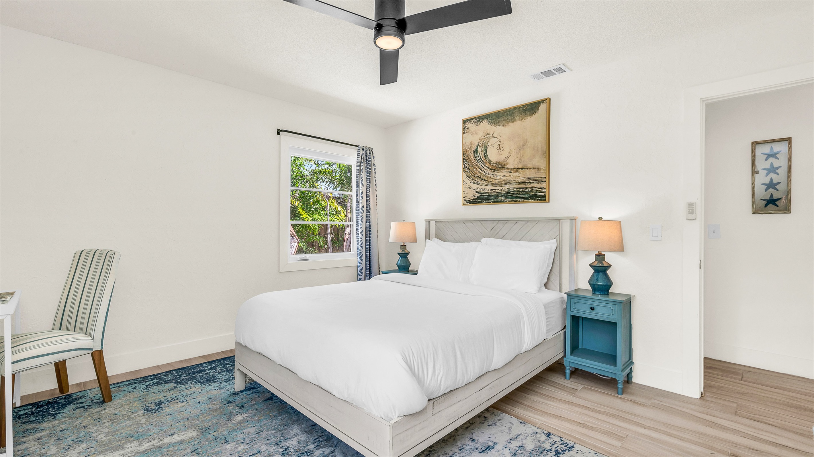 Bedroom 3 features bright coastal decor, crisp white linens, and pops of ocean blue- creating a serene and cheerful retreat for guests to relax and unwind in comfort.