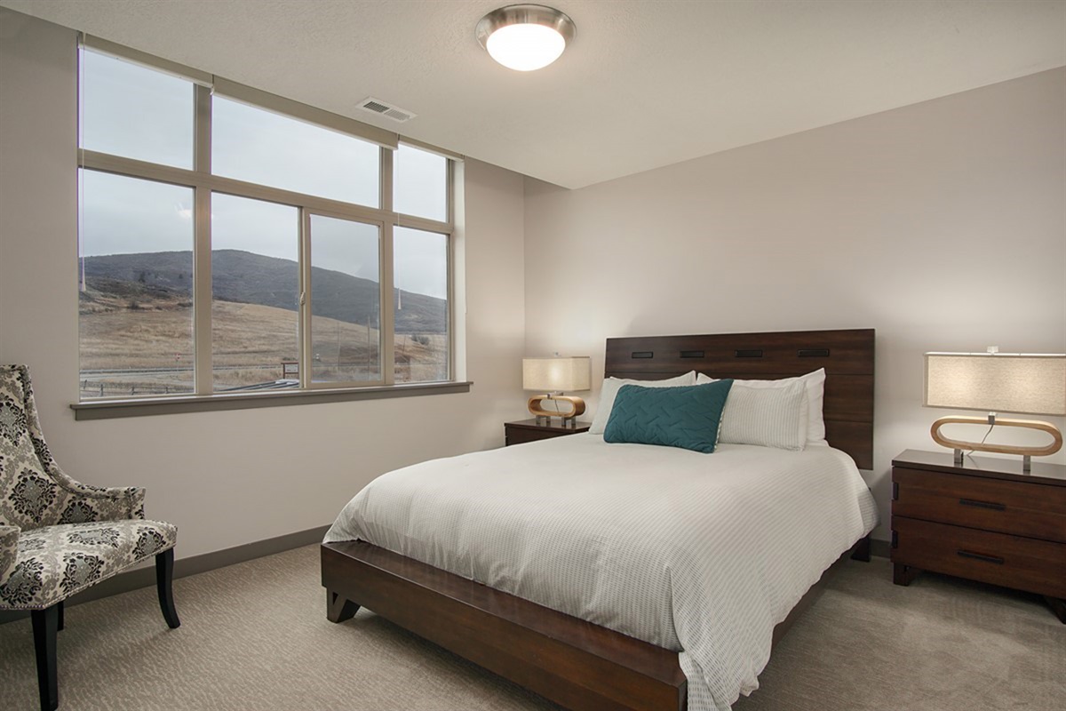 A welcoming guest bedroom featuring a queen bed, soft lighting, and a tranquil atmosphere for restful stays.
