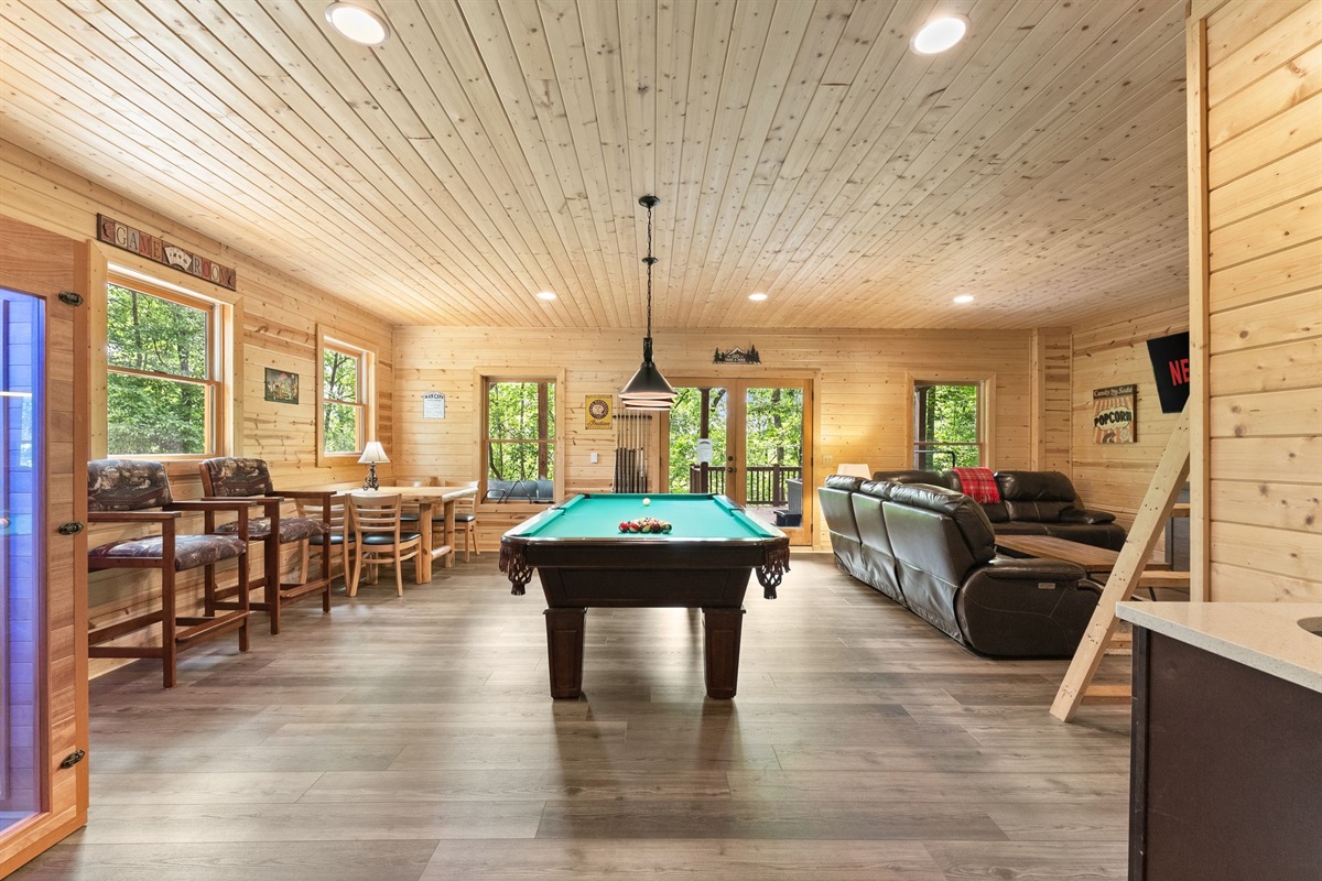 Lower-level entertainment room featuring comfortable lounge seating, a TV, and pool table for the perfect cabin game night.