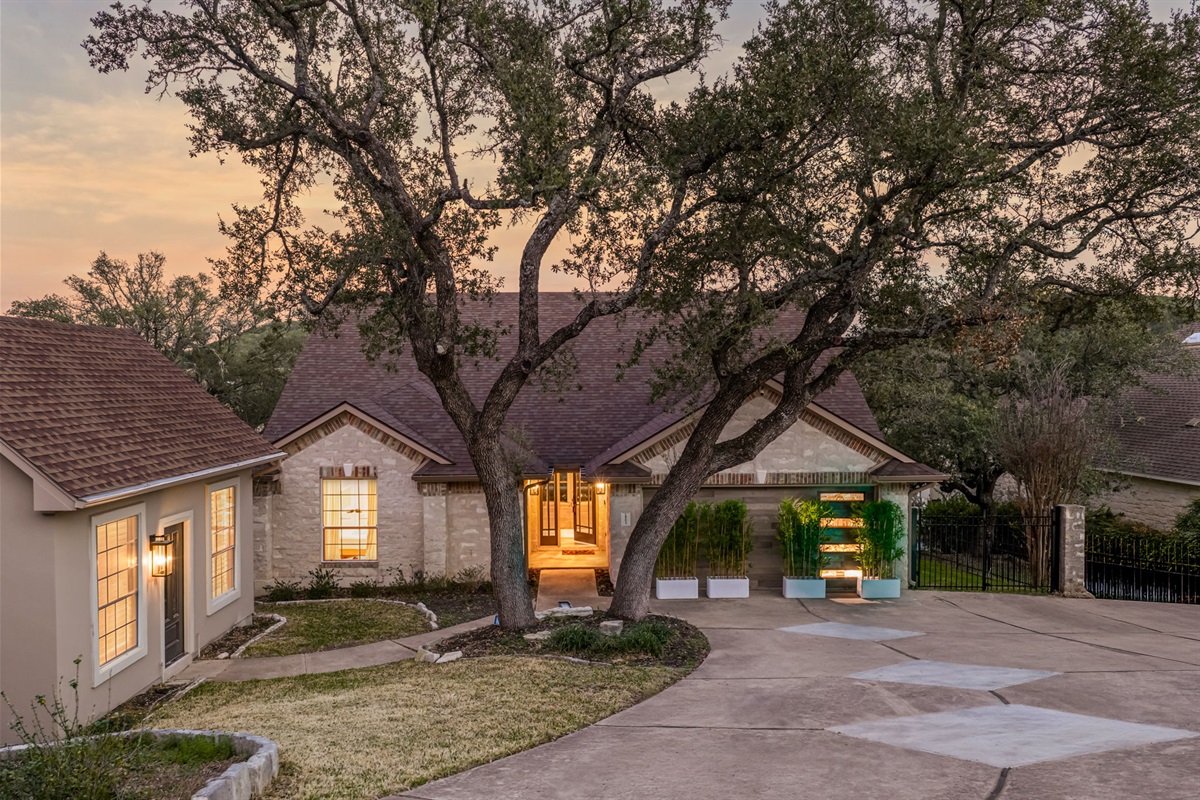 Welcoming front exterior at dusk with mature trees and spacious driveway.