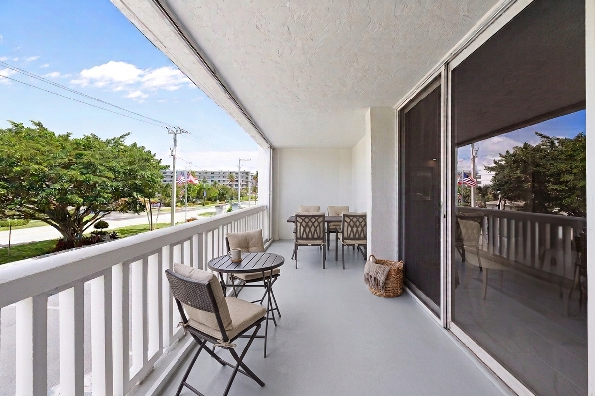 Two outdoor areas — a front balcony overlooking the street and a walk-out patio with direct access to the pool, beach, and fitness center.