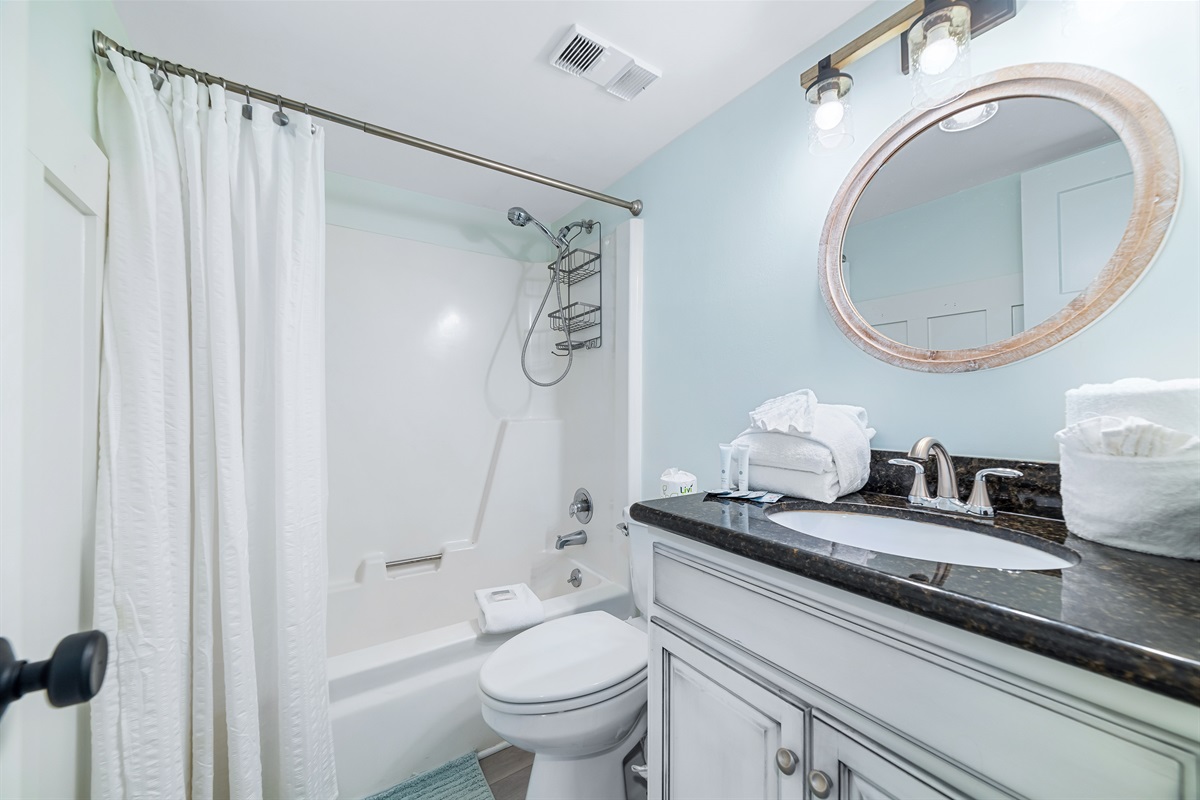 This well-lit guest bathroom offers ample space, shower/tub combo, and essential amenities.  A clean and inviting retreat.