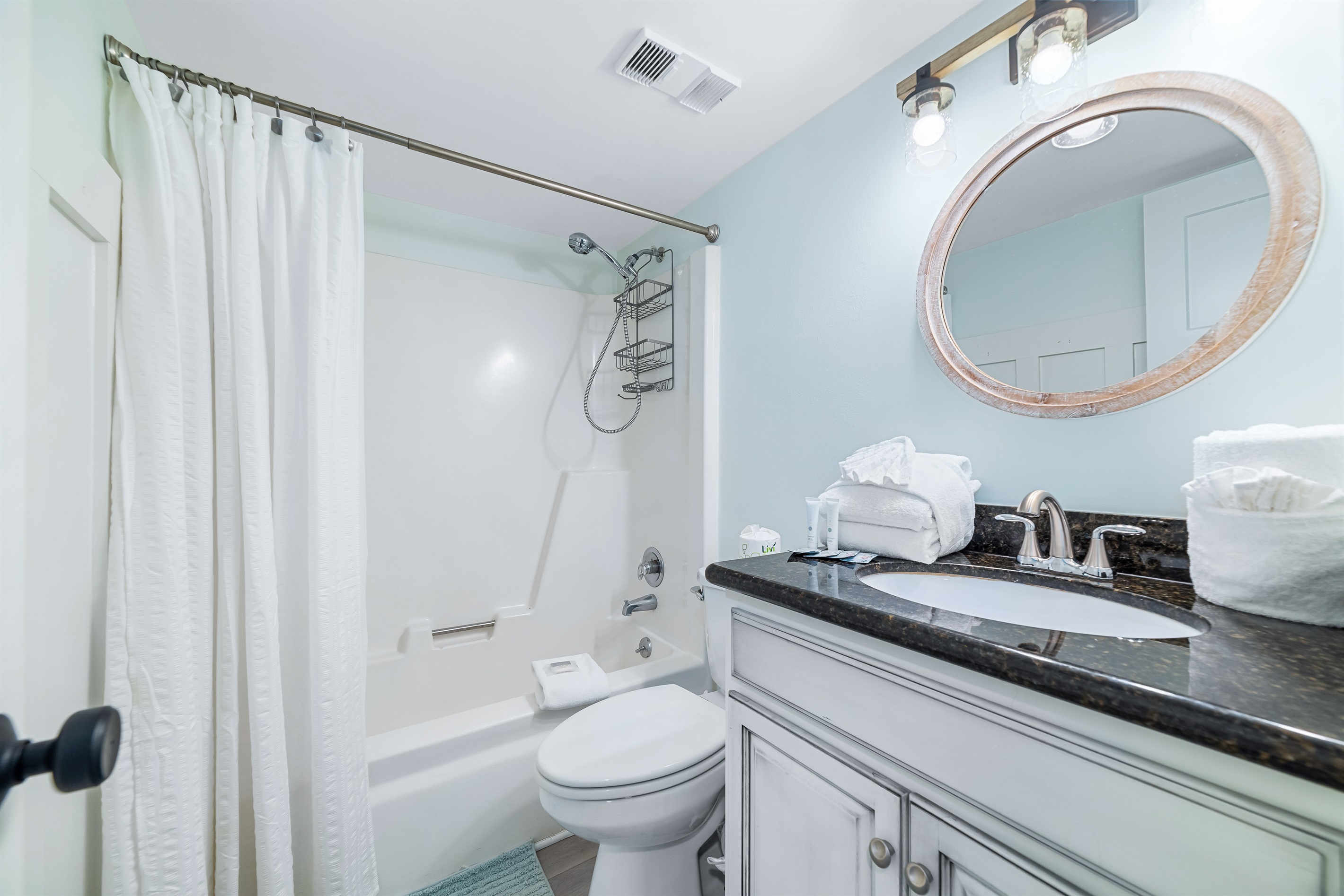 This well-lit guest bathroom offers ample space, shower/tub combo, and essential amenities.  A clean and inviting retreat.