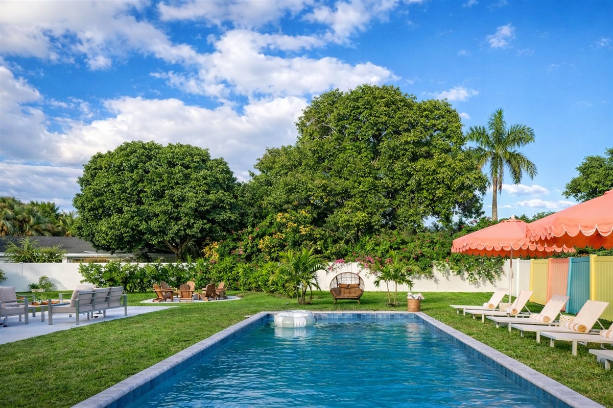 A sun-drenched Palm Beach oasis—brand-new heated saltwater pool with chic in-pool loungers, plush sunbeds, and iconic peach umbrellas, all set within a private, resort-style backyard made for long, lazy afternoons.