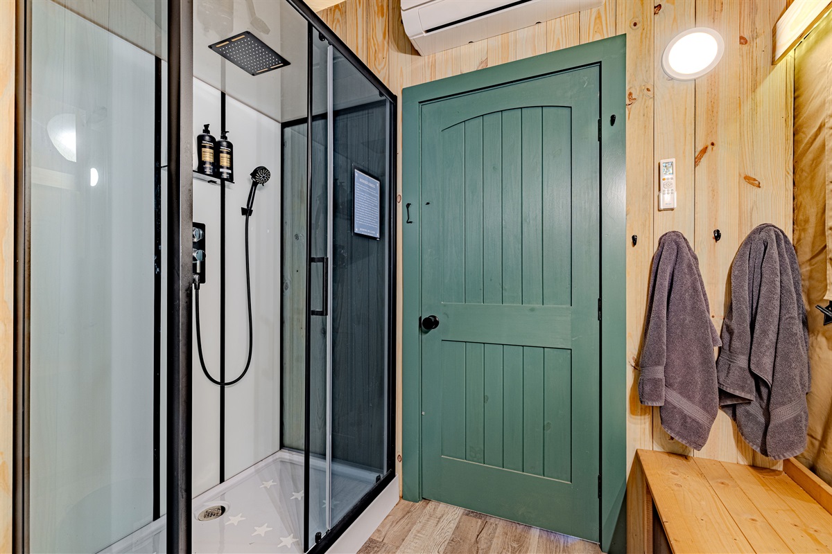 Your private, full-service bathroom. This fully enclosed shower features a rain head and hand-held nozzle, ensuring a refreshing and modern experience that leaves the "camping" part behind.