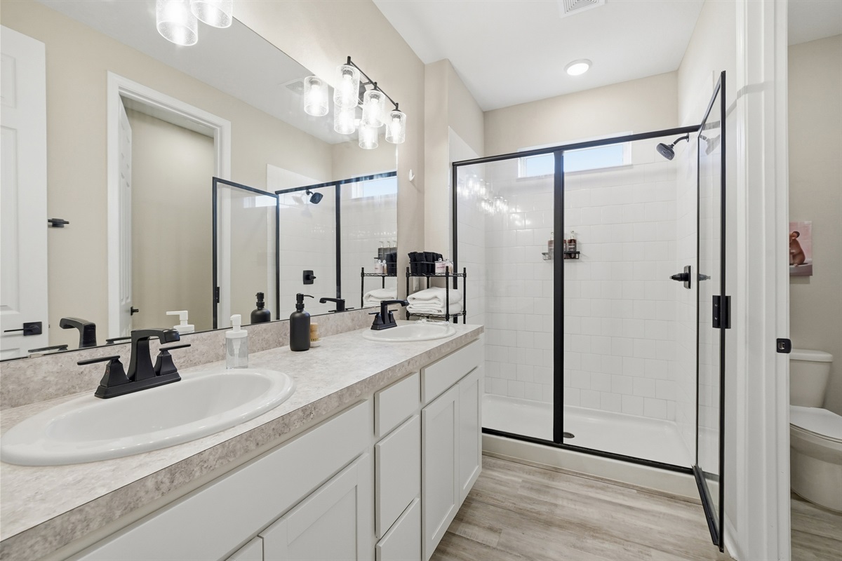 Private master bathroom with dual sinks and glass door shower
