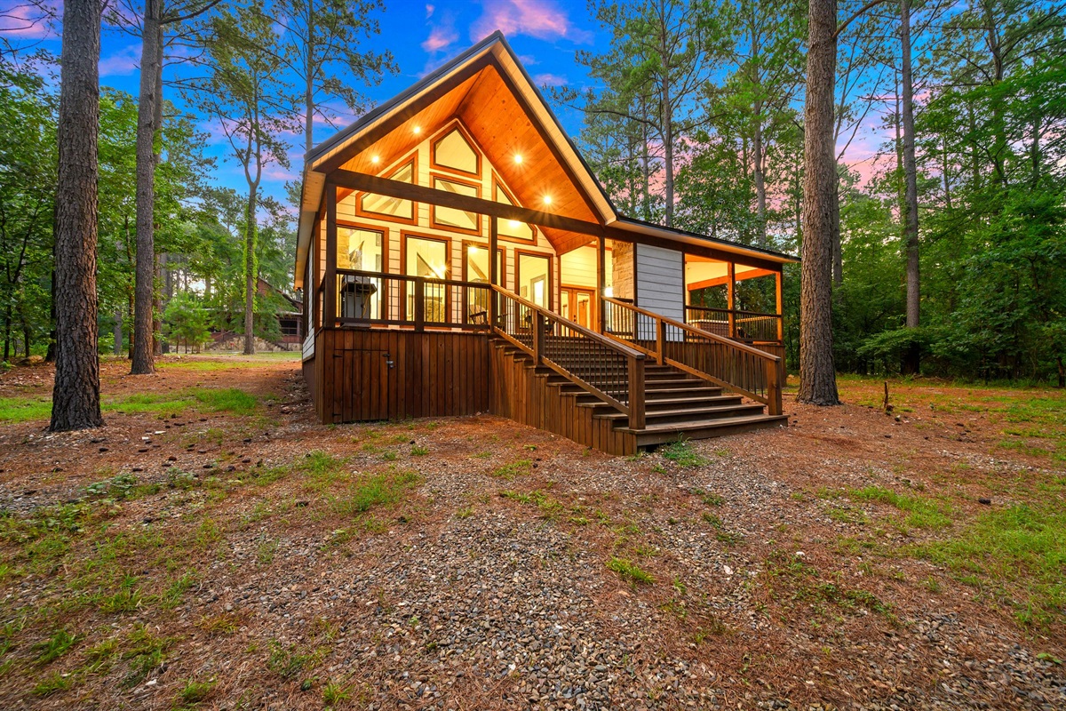 Exterior Retreat: Enjoy stunning wooded views from the spacious deck of this charming cabin!