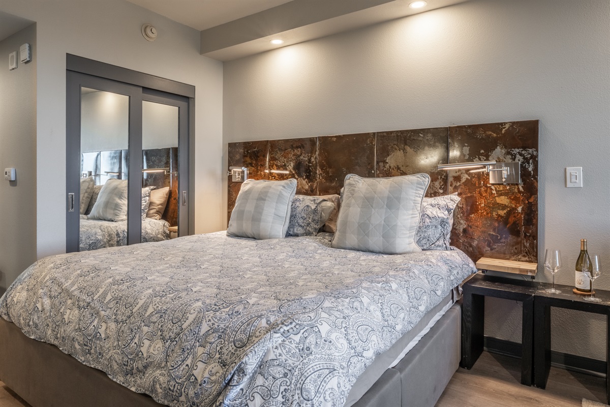 The king bed features a custom metal headboard, adding a modern, handcrafted touch to the studio’s design.