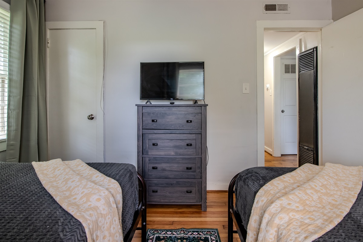 Comfortable twin bedroom with TV and storage, plus a clear view into the hallway for layout reference.