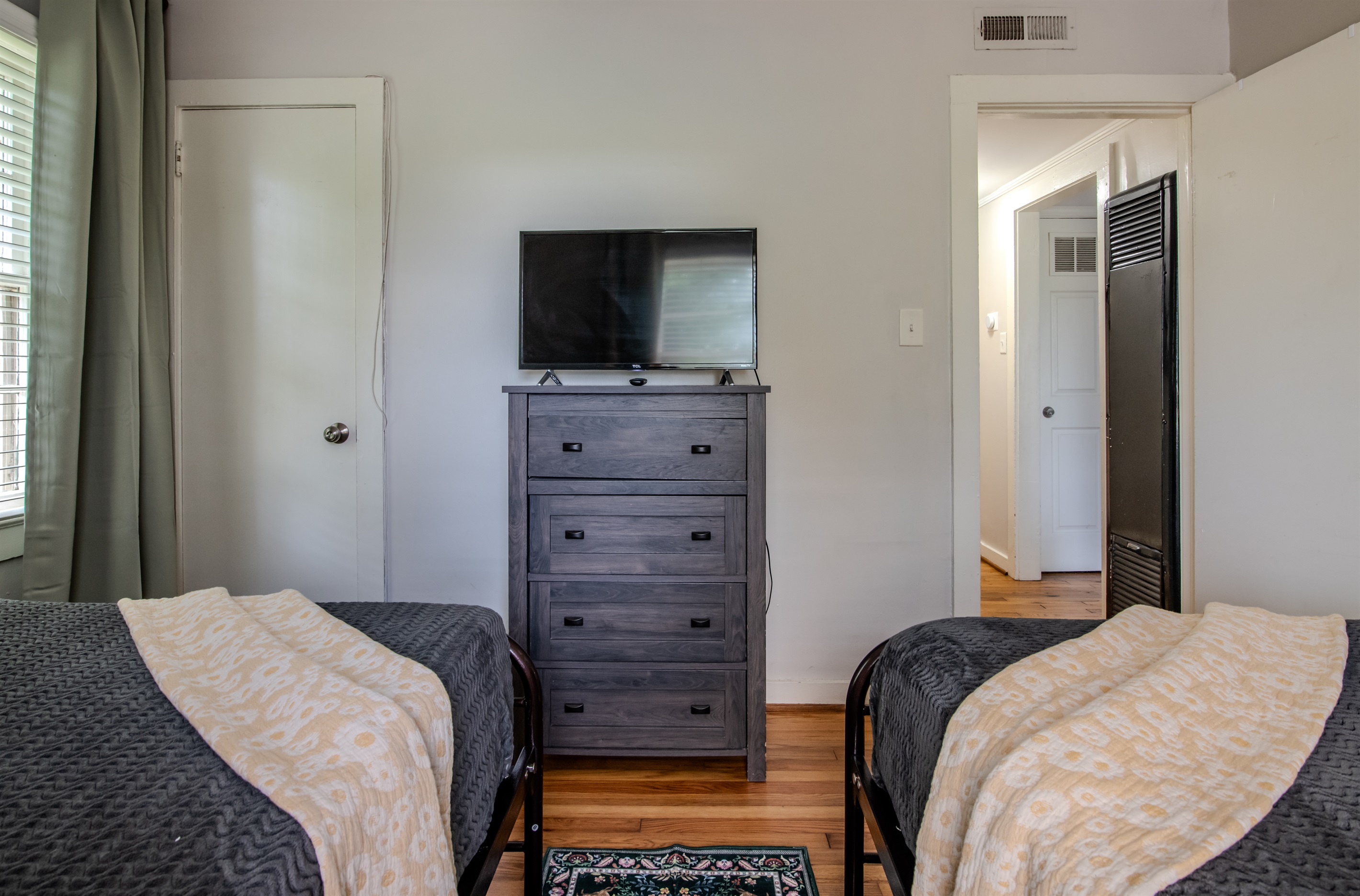 Comfortable twin bedroom with TV and storage, plus a clear view into the hallway for layout reference.