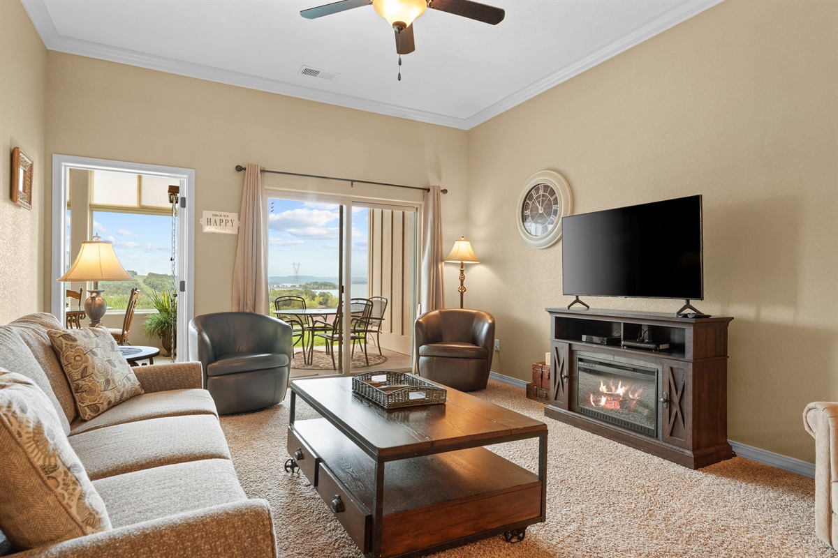 Settle into a comfortable living room with soft seating, an electric fireplace, and light pouring in from the lake side.