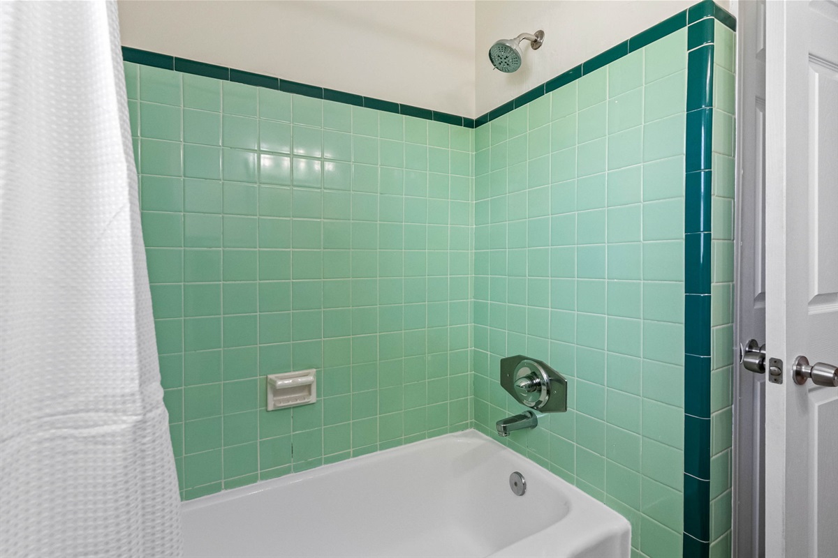 The eye-catching mint-green wall tiles, accented by darker green trim, lend a nostalgic charm that sets this bathroom apart.