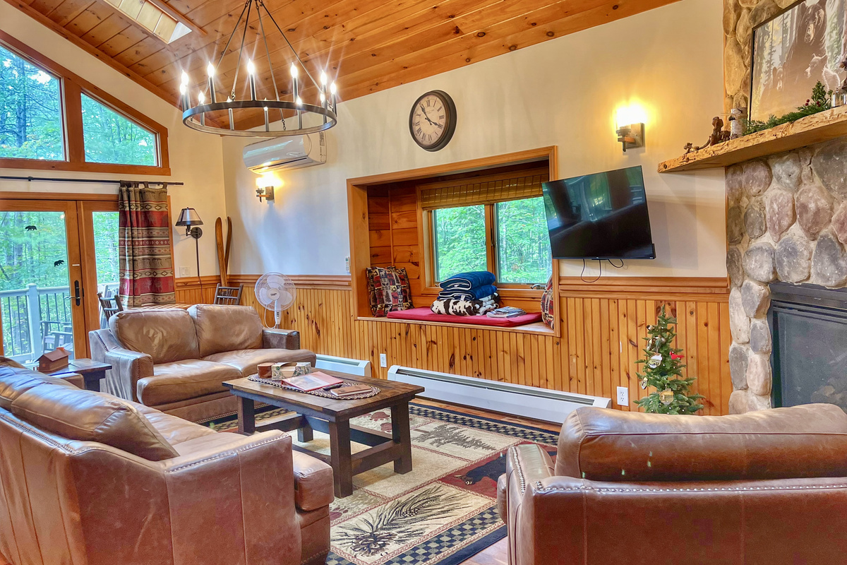 Natural light floods the warm, spacious living area through skylights, a large window seat window, and French doors leading to the expansive deck. 
