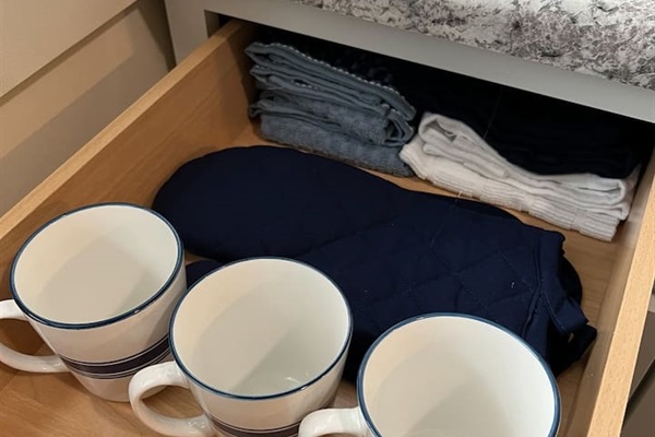 Fully equipped kitchen featuring a cabinet with neatly organized cups, a rag for the granite table, and a stylish design that blends practicality with modern elegance—perfect for an organized and functional cooking space