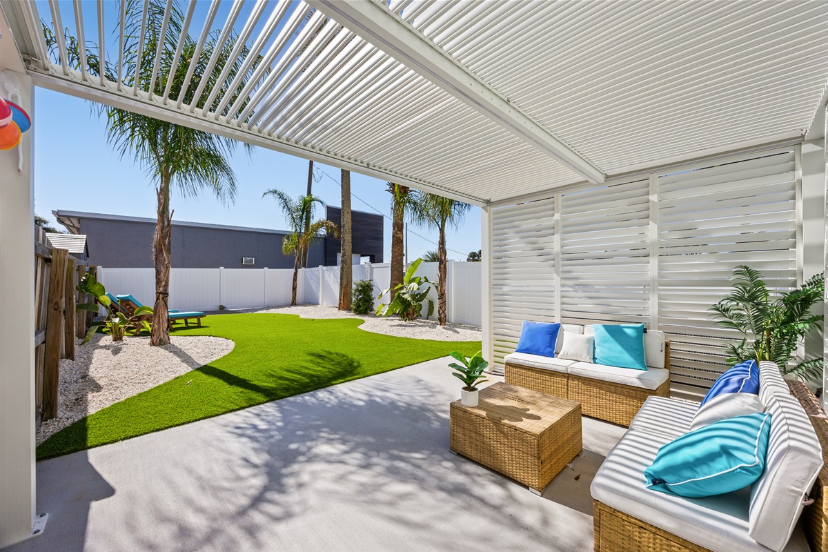 Shaded pergola lounge with comfy seating and turf yard views