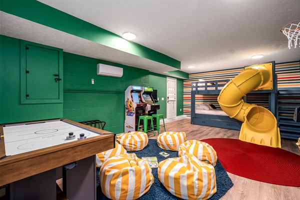 Children's bunk room with tube slide, arcade games, TV, childrens books, air hockey, bean bag chairs and lots of room to play