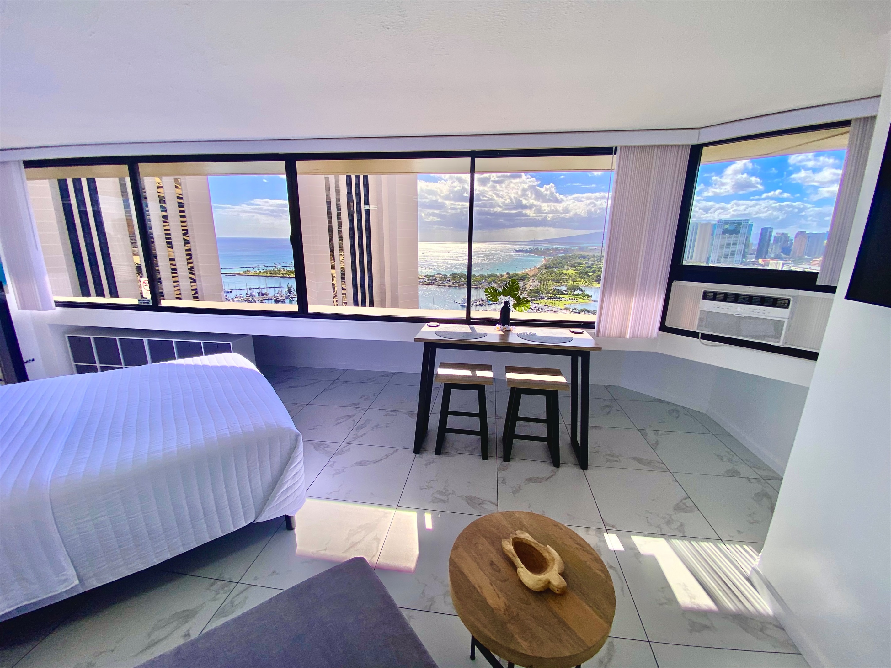 Wake up to panoramic ocean and harbor views stretching across the Honolulu coastline. This elegant Waikīkī studio offers floor-to-ceiling windows, modern finishes, and the perfect space to enjoy breakfast with a view of paradise.