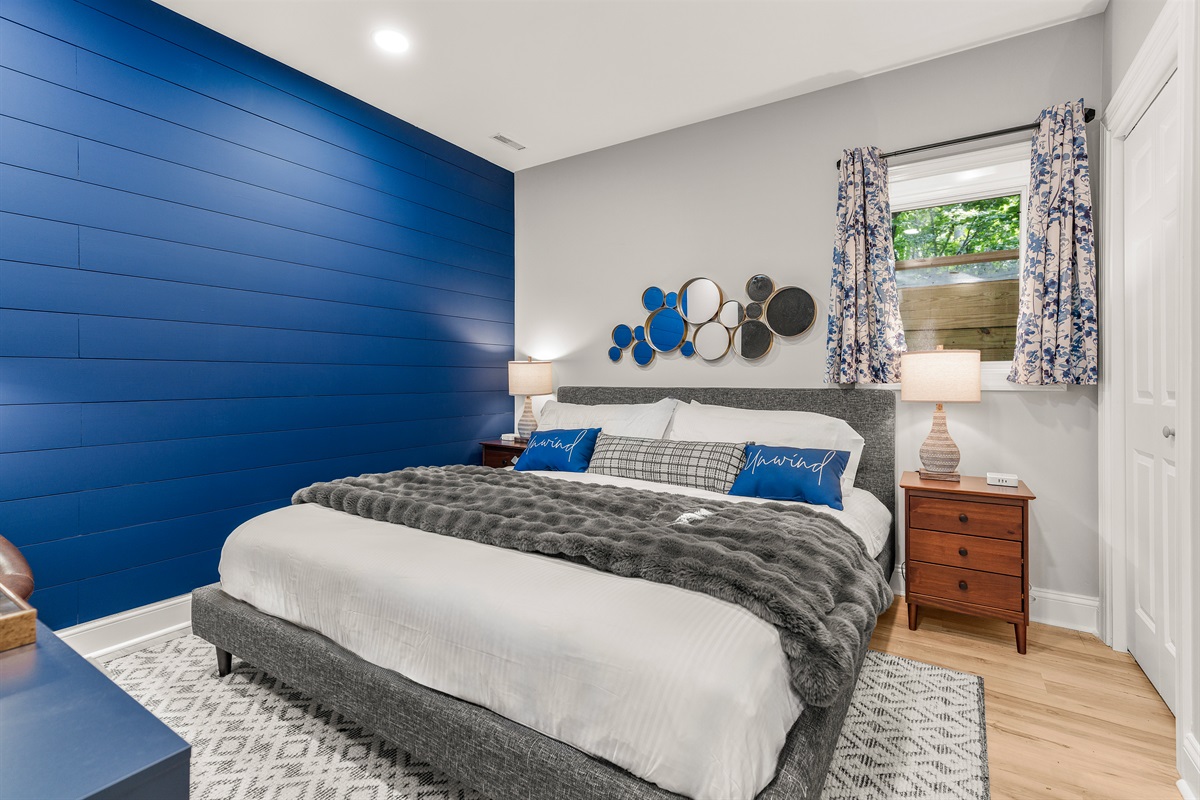 Vivid style meets cozy comfort in this king room—anchored by a bold shiplap feature wall and dressed in calming blue tones. Smartly designed with a 65” TV, cozy chair, and just the right pop