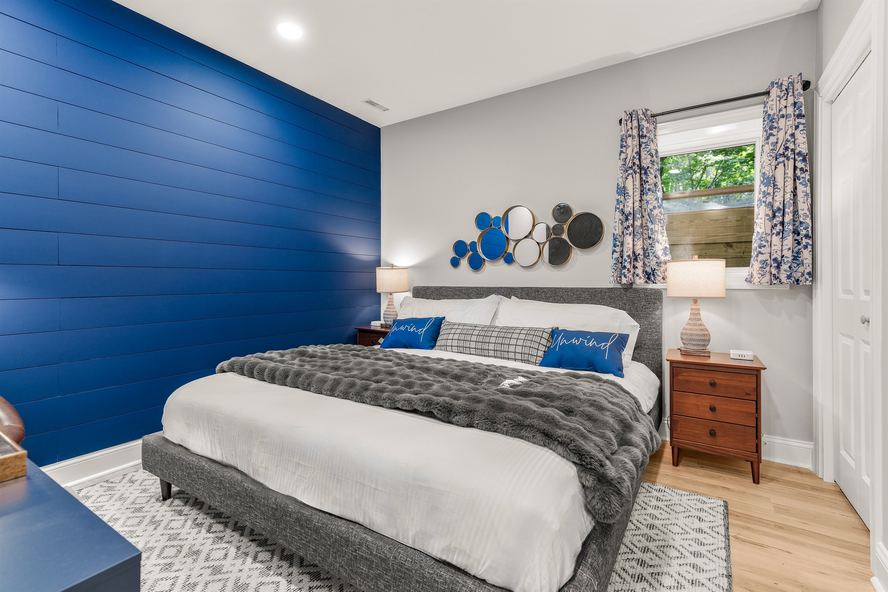 Vivid style meets cozy comfort in this king room—anchored by a bold shiplap feature wall and dressed in calming blue tones. Smartly designed with a 65” TV, cozy chair, and just the right pop