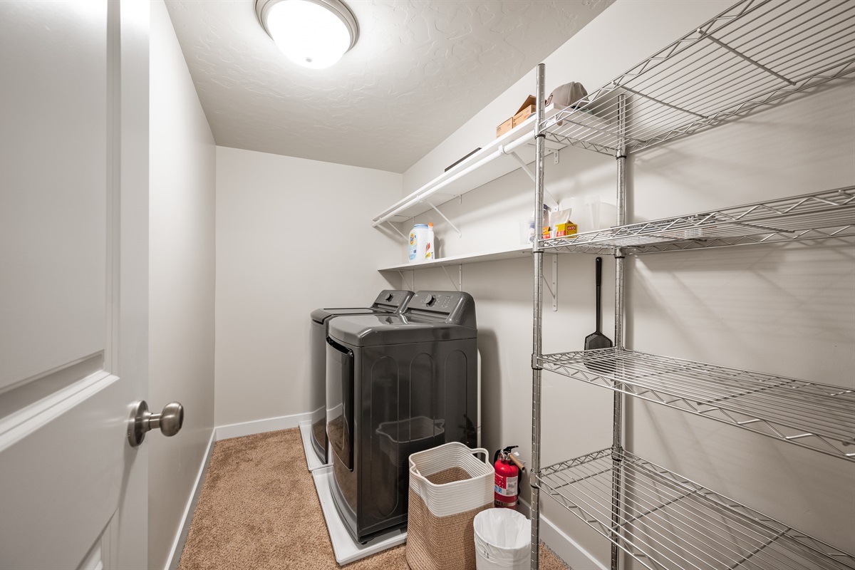 The downstairs unit includes a private laundry room with a washer, dryer, and plenty of shelving for storing laundry essentials and personal items.