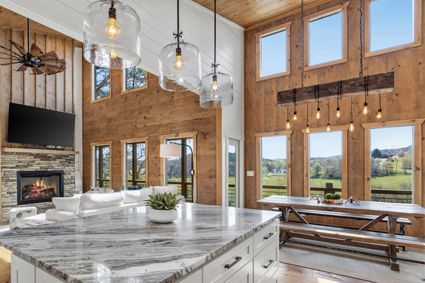 Gourmet kitchen with a massive stone island, white shaker cabinets, and stunning floor-to-ceiling windows overlooking the pasture and mountains. Fully equipped for baking with all the tools you need to cook and entertain with ease.