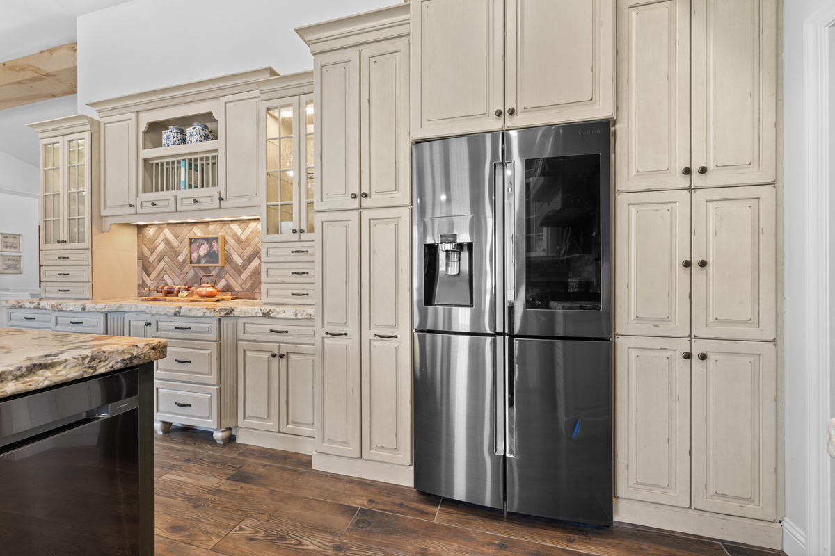 The beautifully appointed kitchen features custom cabinetry, generous storage, a sleek stainless-steel refrigerator, and refined finishes throughout.