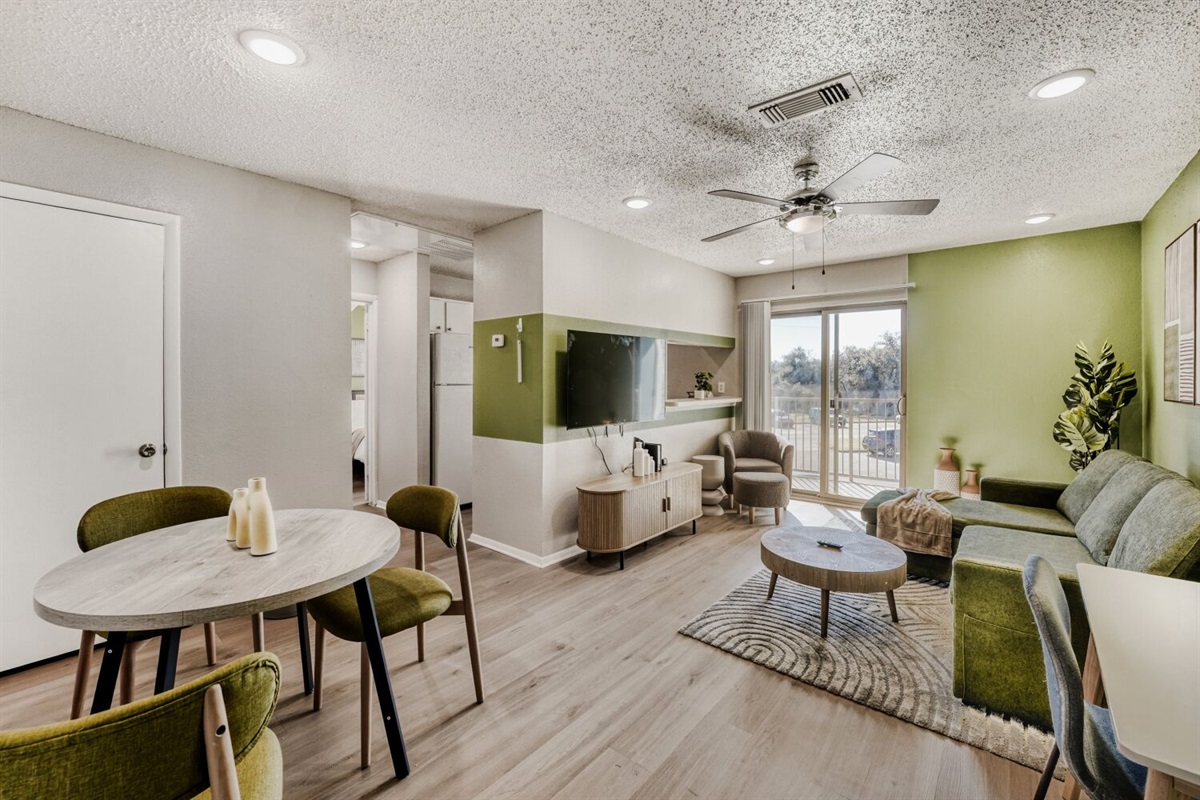 Bright open-concept living space with modern green accents and natural light.