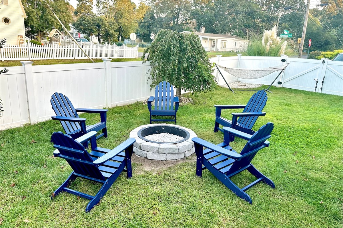 The perfect spot for s'mores and stories! This backyard setup features a cozy stone fire pit surrounded by classic blue Adirondack chairs. There’s even a hammock in the corner for those lazy afternoon naps in the sun.