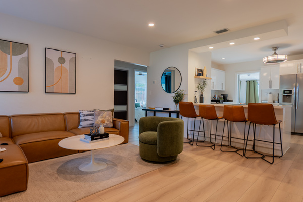 Open living area with sectional sofa, swivel chair, and kitchen bar seating