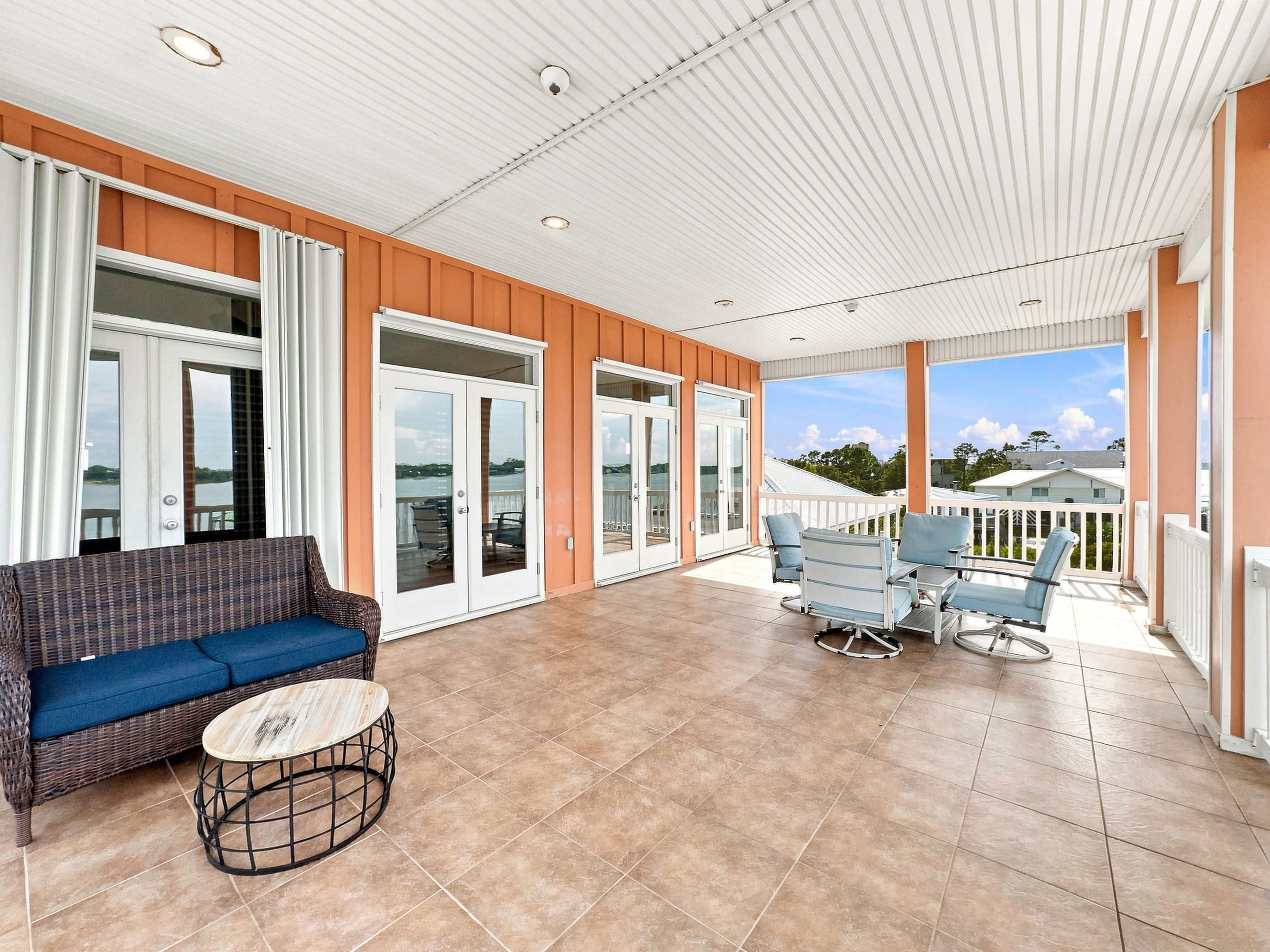 Bright sunroom porch with lounge seating and lagoon views