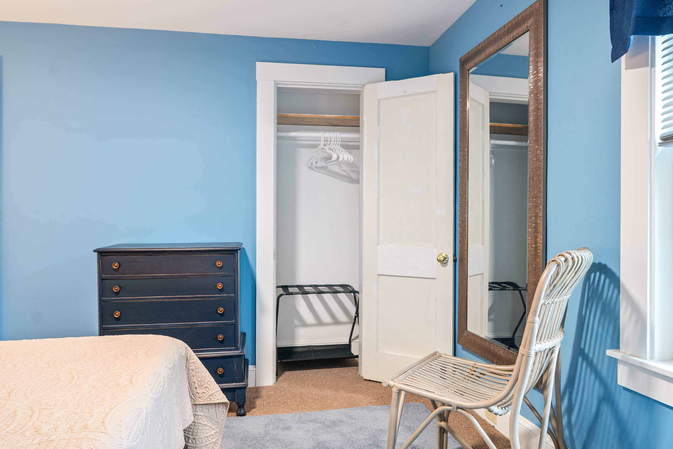 This layout perspective showcases the extensive guest storage options inside the primary bedroom. Combining a multi-drawer dresser and an open wardrobe closet with direct access to a full-length dressing mirror, this suite prioritizes utility.