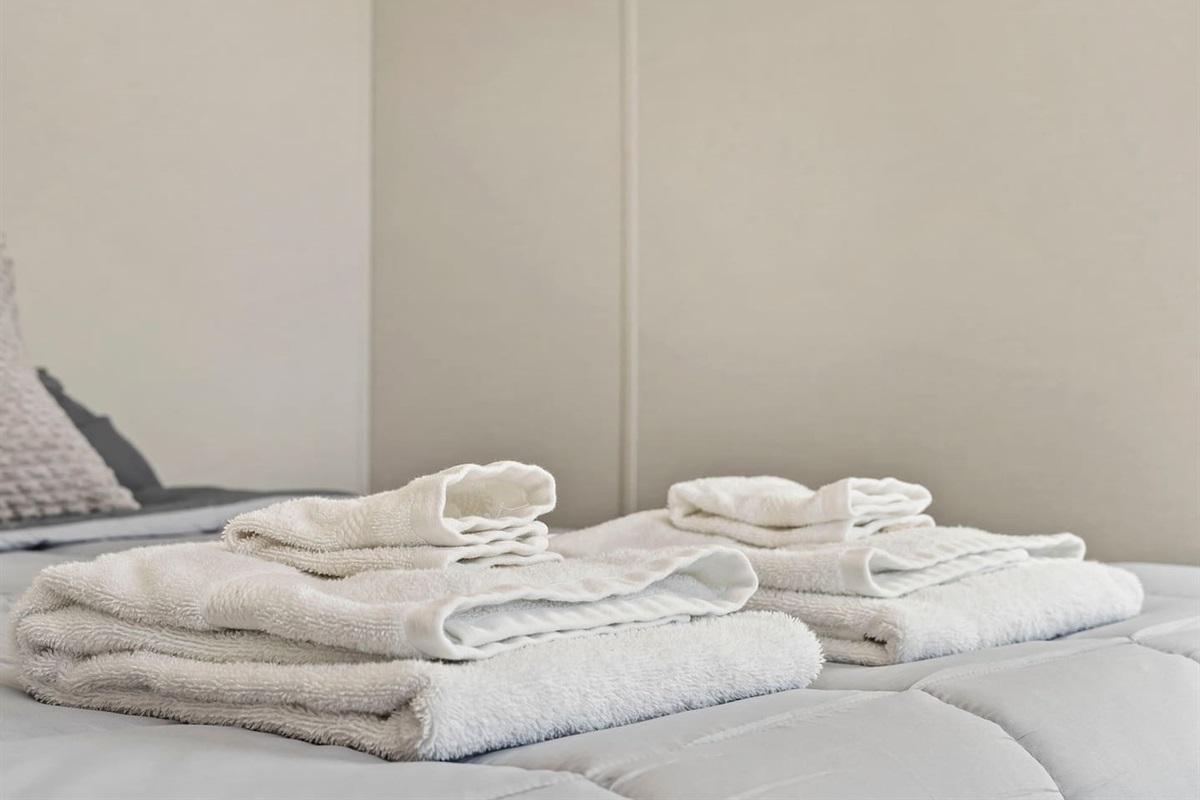 Fresh towels neatly prepared on the queen bed, adding a hotel-style touch for your arrival.