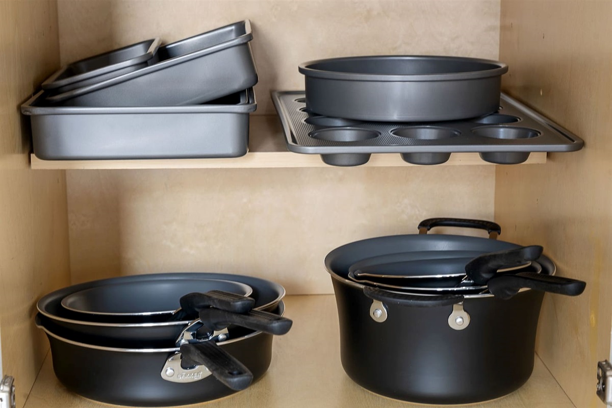 Find everything you need in this neatly arranged kitchen cabinet, stocked with a variety of cookware. Ideal for preparing any meal with ease.