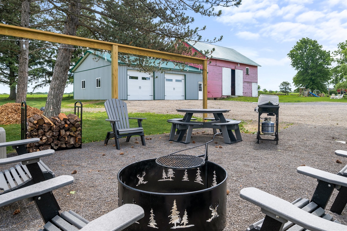 Fire pit and grill area overlooking scenic barns—perfect for family BBQs and starry nights