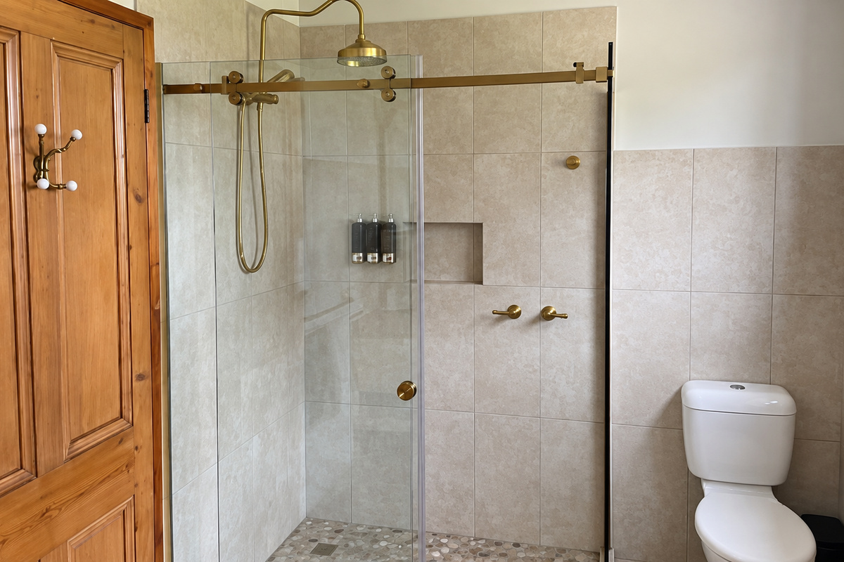 A glass walk-in shower, brass fittings, tiled walls and built-in niche give this bathroom a clean, easy setup for everyday use.