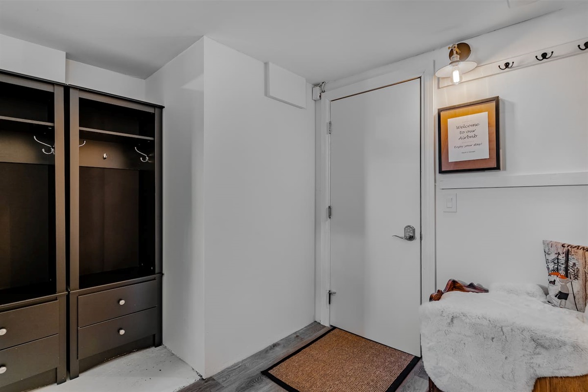 Basement entry with a smart leaver lock on the door. Your unique code will the the same as the code for the deadbolt in the exterior back door. Open storage for coats, shoes, and outdoor gear
