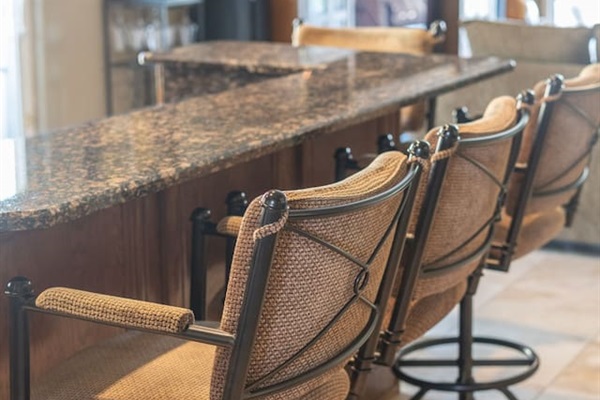 Three cushioned bar stools line the granite island — a great spot for casual meals, morning coffee, or evening cocktails.