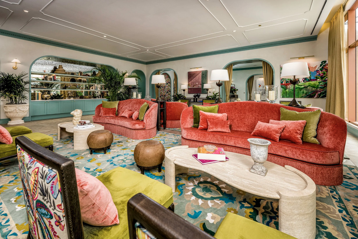 A conservatory-style lounge with coral sofas and towering palms - resort living reimagined for everyday.