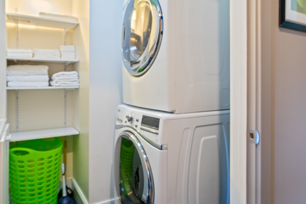 Effortless extended stays at "The Crag." This dedicated laundry nook features a high-efficiency stacked washer and dryer, paired with fully stocked shelving for fresh towels and linens ready for your Maine adventures.