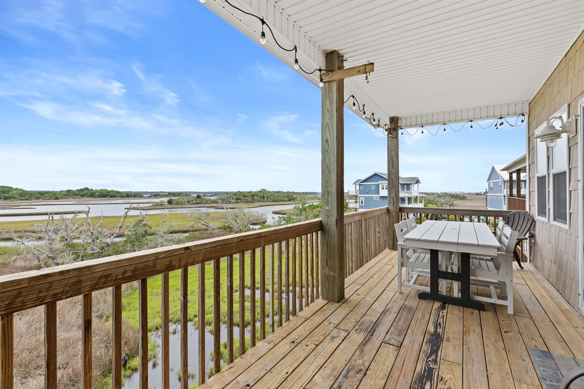 Spacious covered deck with outdoor dining and peaceful marsh views