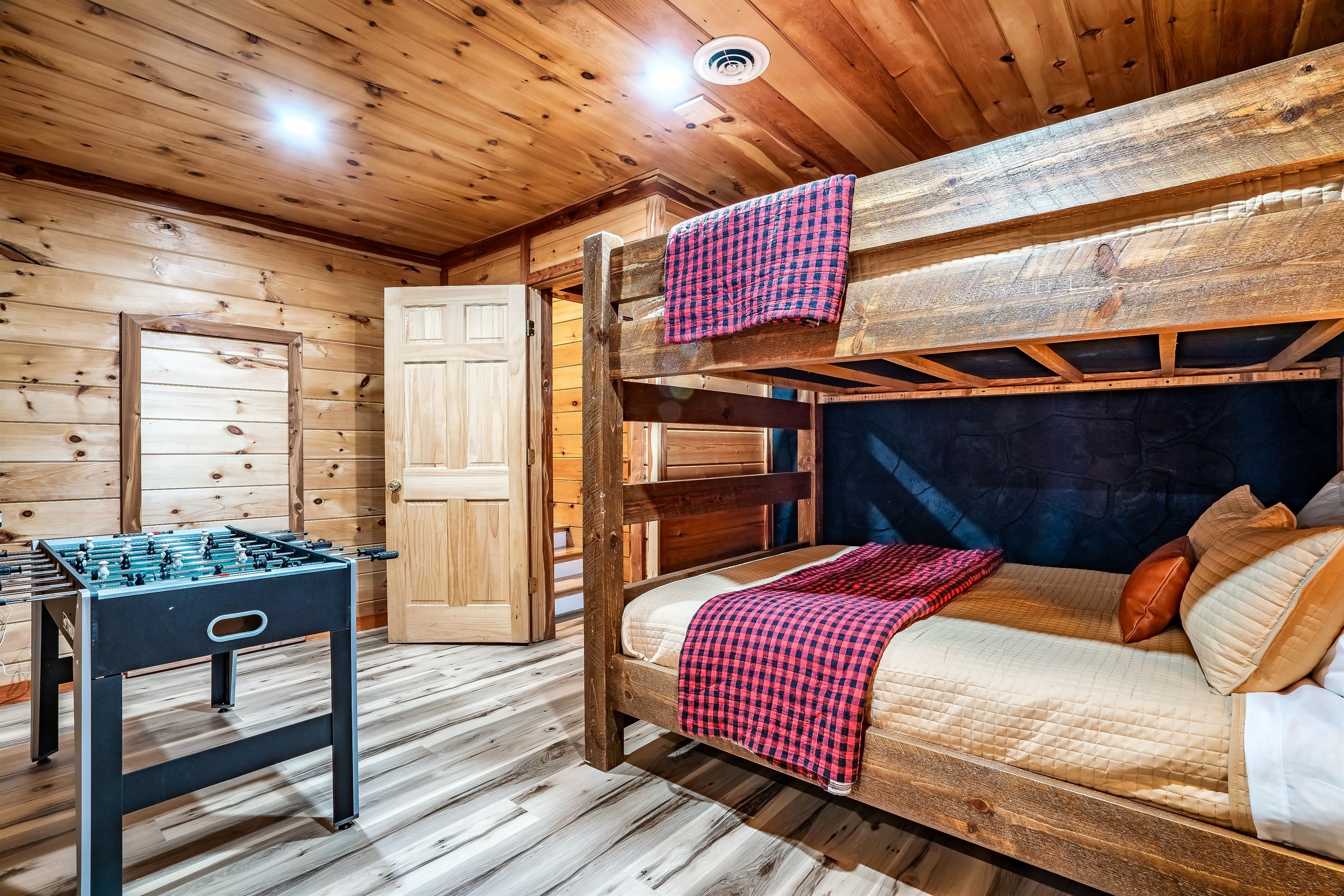 Fun and cozy mountain cabin game room featuring a Queen bunk bed, perfect for kids, families, and group getaways filled with games and adventure.