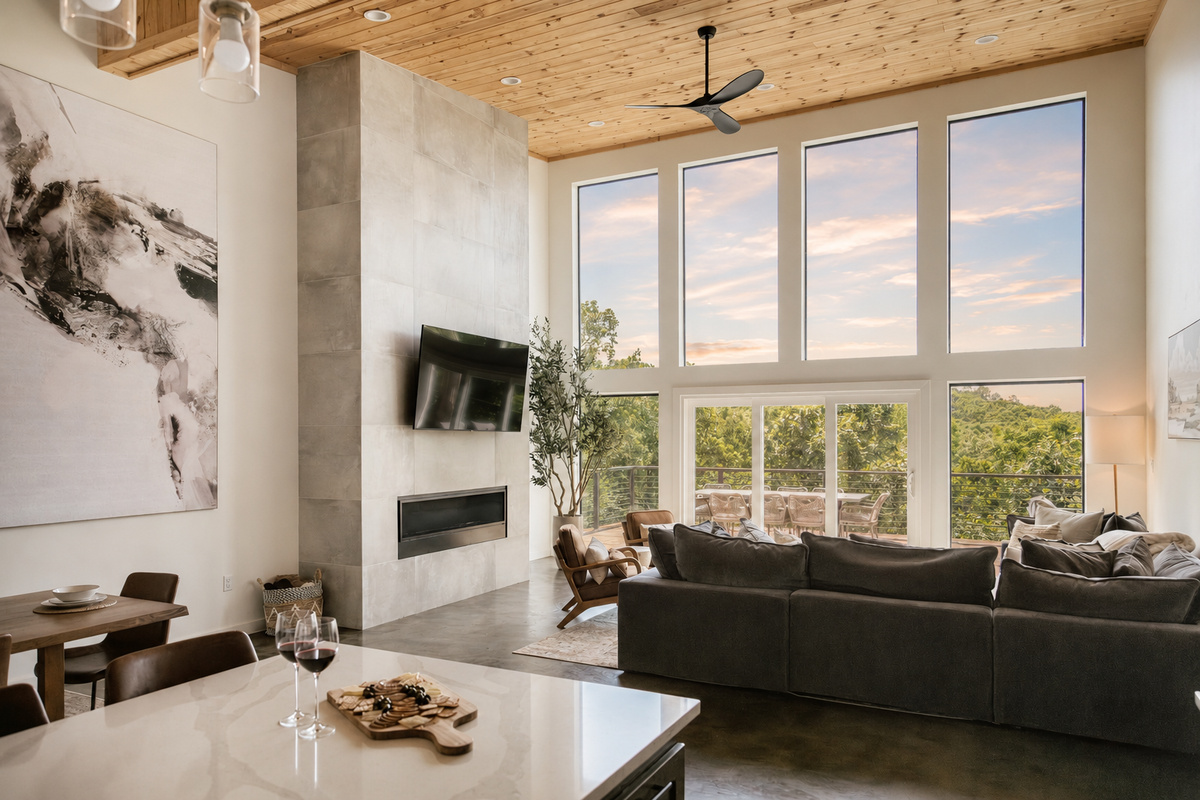 Expansive living space featuring floor-to-ceiling windows, premium furniture, smart TV, and access to the outdoor deck.