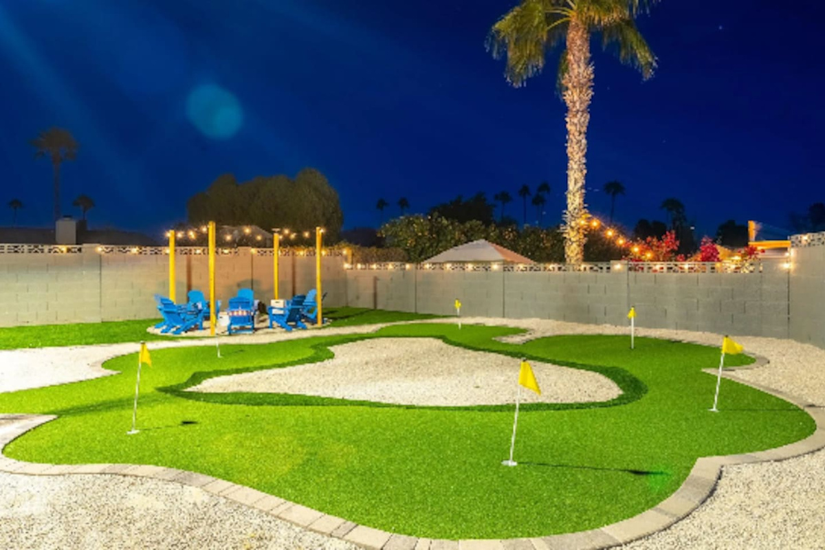 A backyard putting green under string lights and palm trees, because vacation should include a few rounds of mini golf before bed. Multiple holes mean the whole group can play at once.