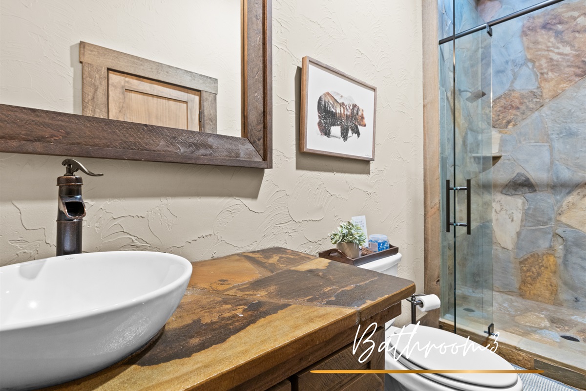 Bathroom 3: features natural stone details, sleek fixtures, and a glass-enclosed shower for added elegance.