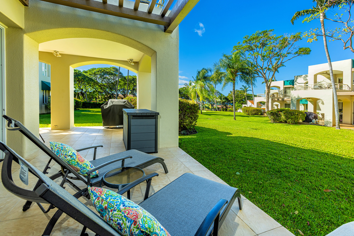 View from the chaise lounges onto a large lawn (behind you is the sliding door to the bedroom). Note the BBQ has been removed from all lanais in May 2024. There are now common BBQ areas around the property
