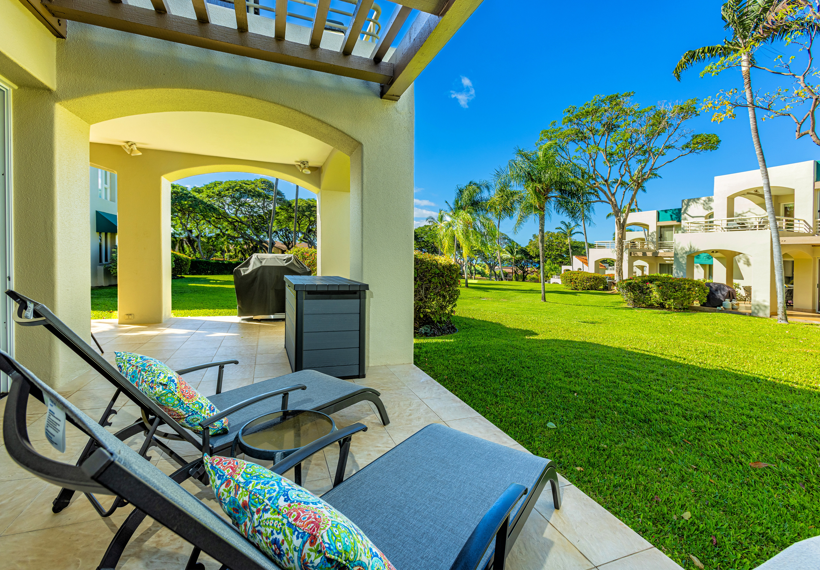View from the chaise lounges onto a large lawn (behind you is the sliding door to the bedroom). Note the BBQ has been removed from all lanais in May 2024. There are now common BBQ areas around the property