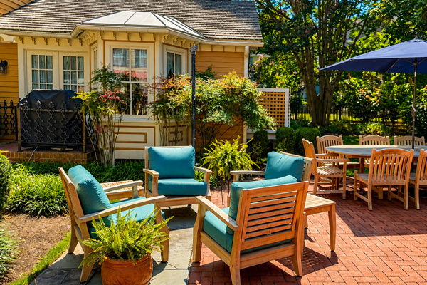 The private rear patio — teak seating, outdoor dining for the full group, and a gas grill tucked in the garden. Fully fenced and completely yours for the stay