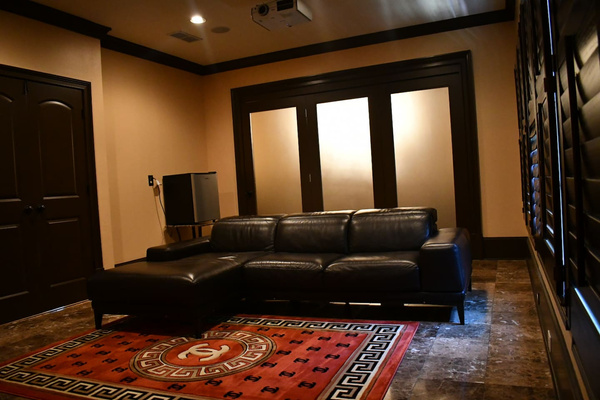 Tv sitting area attached to master bedroom with large projector screen.