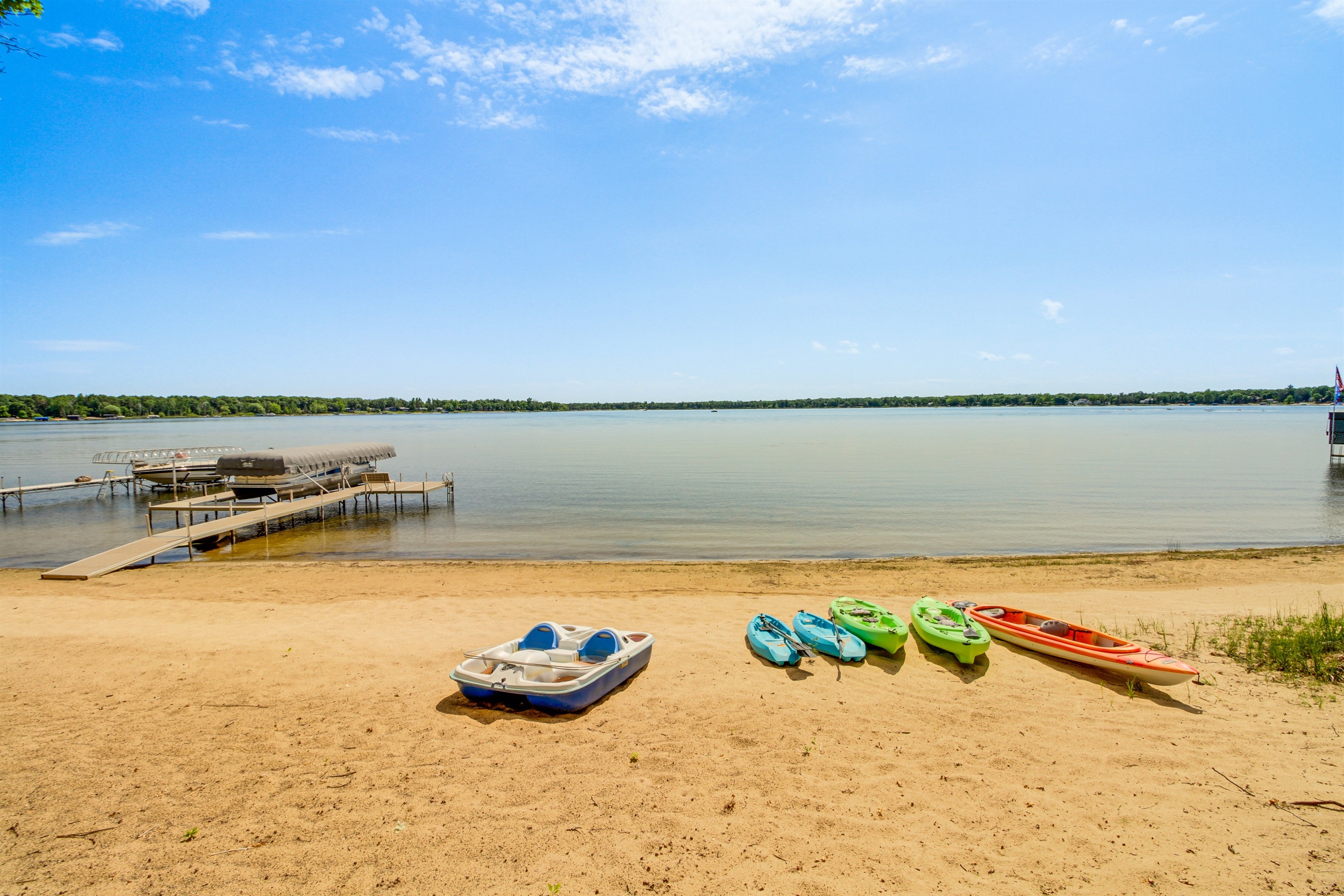 Sandy beach frontage with kayaks and a paddle boat ready for lake adventures